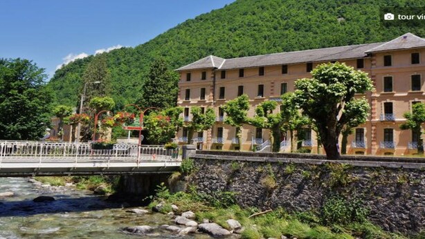 Un hôtel situé au bord de la rivière, doté d’un mur en pierre et d’un pont.