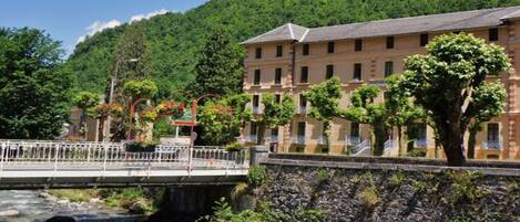 A riverside hotel with a stone wall and a bridge.