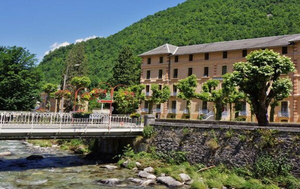 A riverside hotel with a stone wall and a bridge.