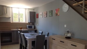 Une cuisine moderne avec une table à manger, des chaises, un four à micro-ondes et une horloge au mur.