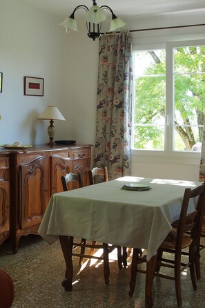 A dining area with a table, chairs, a lamp, a cabinet, and a window with curtains. - In a privileged setting, detached house, private swimming pool, pets allowed (Sisteron)