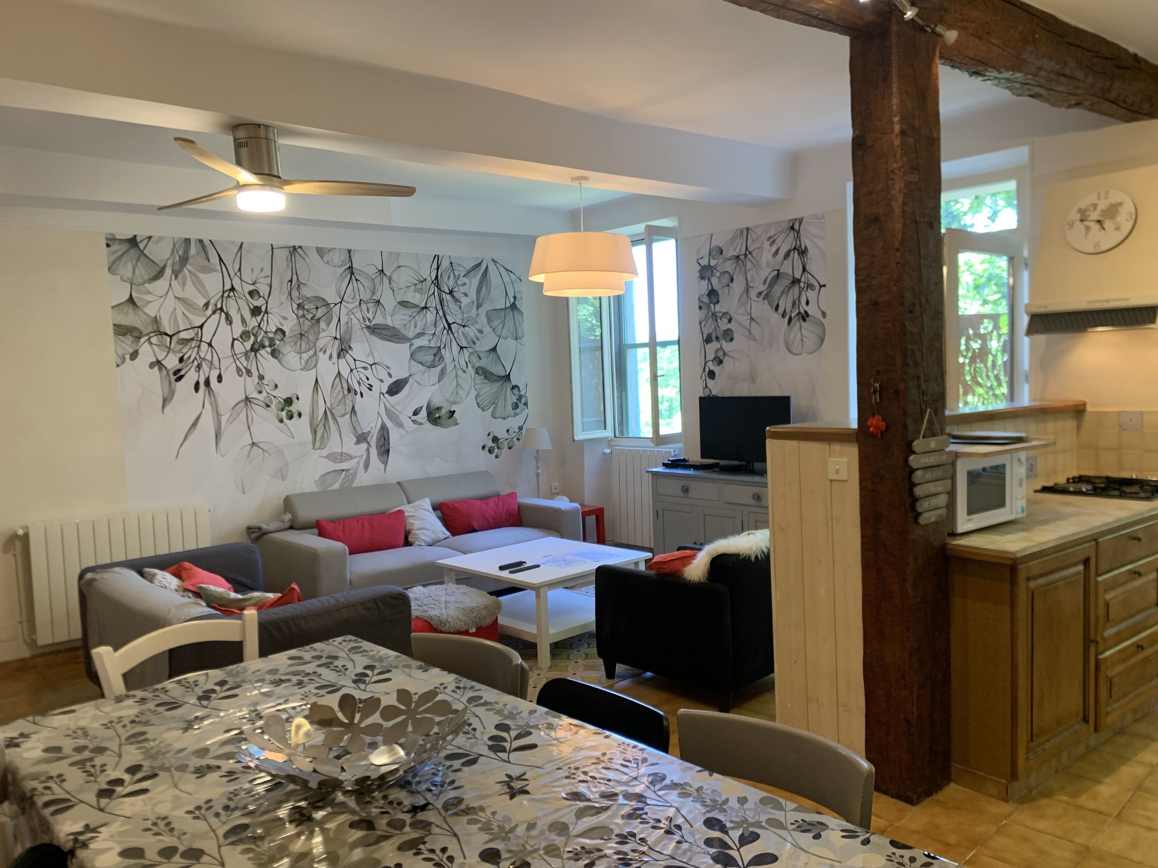 Ein gemütliches Wohnzimmer mit einer Couch, einem Esstisch und einem Fernseher. Es gibt eine Küchenzeile mit einer Mikrowelle und Schränken.