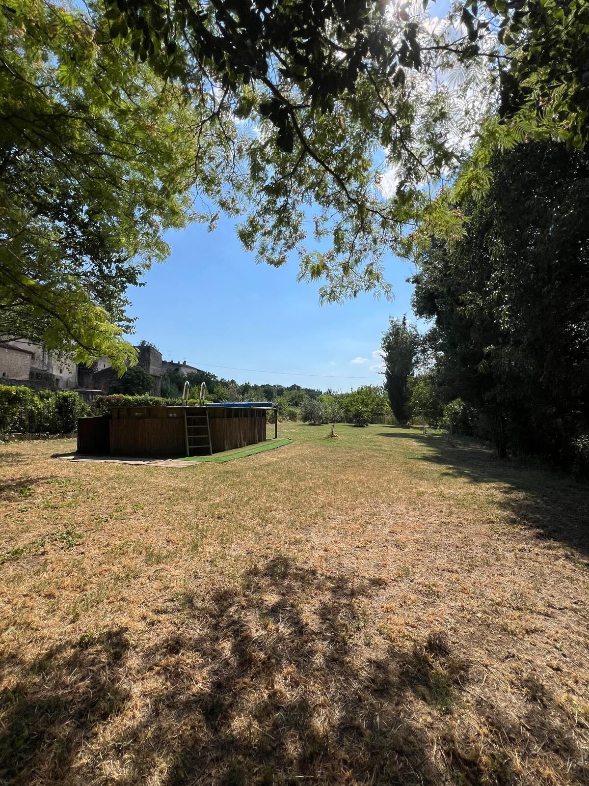 A grassy outdoor area with a wooden structure, possibly a shed or storage unit, and a clear sky.
