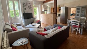 A spacious living area with a sofa, a coffee table, and a television. There is a kitchen area with cabinets and a refrigerator. - Country house with large garden and swimming pool (Carces)