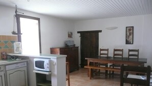 A kitchen with a microwave, coffee maker, and a dining table with chairs. - A gîte of character and grand comfort in the heart of nature  3*** (St Laurent le Minier)