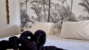 A bedroom with a bed, pillows, a woven basket, and a wall mural of palm trees. - Between sea and rivers, at the gates of the Guadeloupe National Park! (capesterre belle eau)