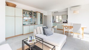 Uma sala de estar moderna com um sofá, mesa de centro e cozinha ao fundo.