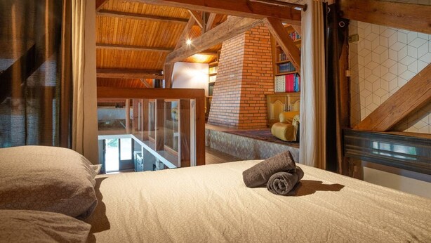 Een slaapkamer met een bed, een opgerolde handdoek, een bakstenen openhaard en uitzicht op een balkon.