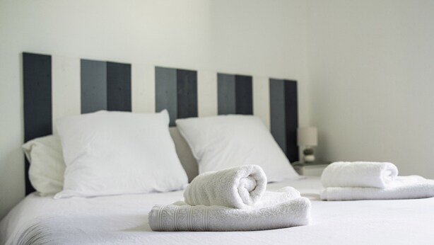 Ein Hotelzimmer mit einem ordentlich bezogenen Bett, weißen Leinen und einem modernen Kopfteil.