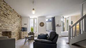 Ein modernes Wohnzimmer mit Steinwänden, einem Ledersofa, einem kleinen Tisch und einem Fernseher.