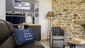 Ein gemütliches Wohnzimmer mit Steinwand, Kamin, einer Ledersofa mit Zierkissen und einer modernen Lampe sowie einem kleinen Tisch.