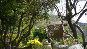 A garden with stone benches, a birdhouse, and a variety of plants. - Sunny villa with stunning views over the village and the sea (Oletta)