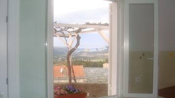 Une pièce dotée d’une grande fenêtre, d’une plante en pot et offrant une vue sur un pont et un paysage.