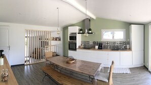 Une cuisine moderne avec une table en bois, des armoires blanches et une grande fenêtre.