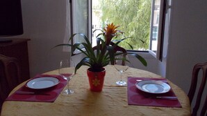 A dining table with two plates, two wine glasses, and a potted plant.