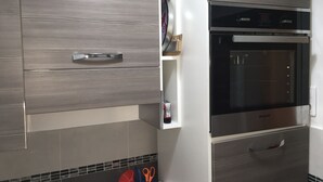 A modern kitchen with built-in appliances, including a microwave and oven, and a storage cabinet.