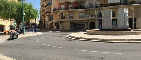 A multi-story building with balconies, a roundabout, and a parked motorcycle.