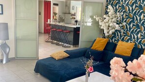 A modern living room with a sofa, a coffee table, and a kitchen area in the background.