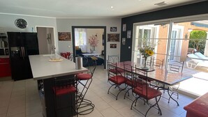 A modern kitchen with a central island, dining area with red chairs, and a view of the outdoors.