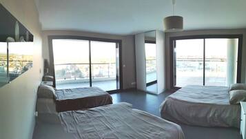 A modern hotel room with two beds, large windows, and a city view.