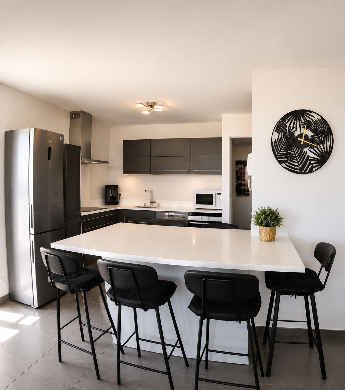 A modern kitchen with a central island, stainless steel appliances, and black bar stools.