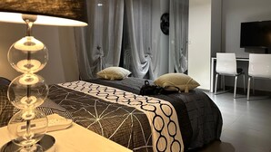 Et moderne soveværelse med seng, skrivebord og fjernsyn.
