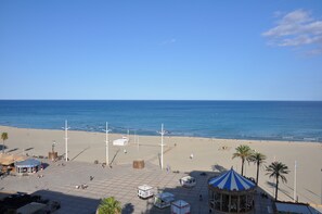 Une plage avec un kiosque, des palmiers et un ciel bleu azur.