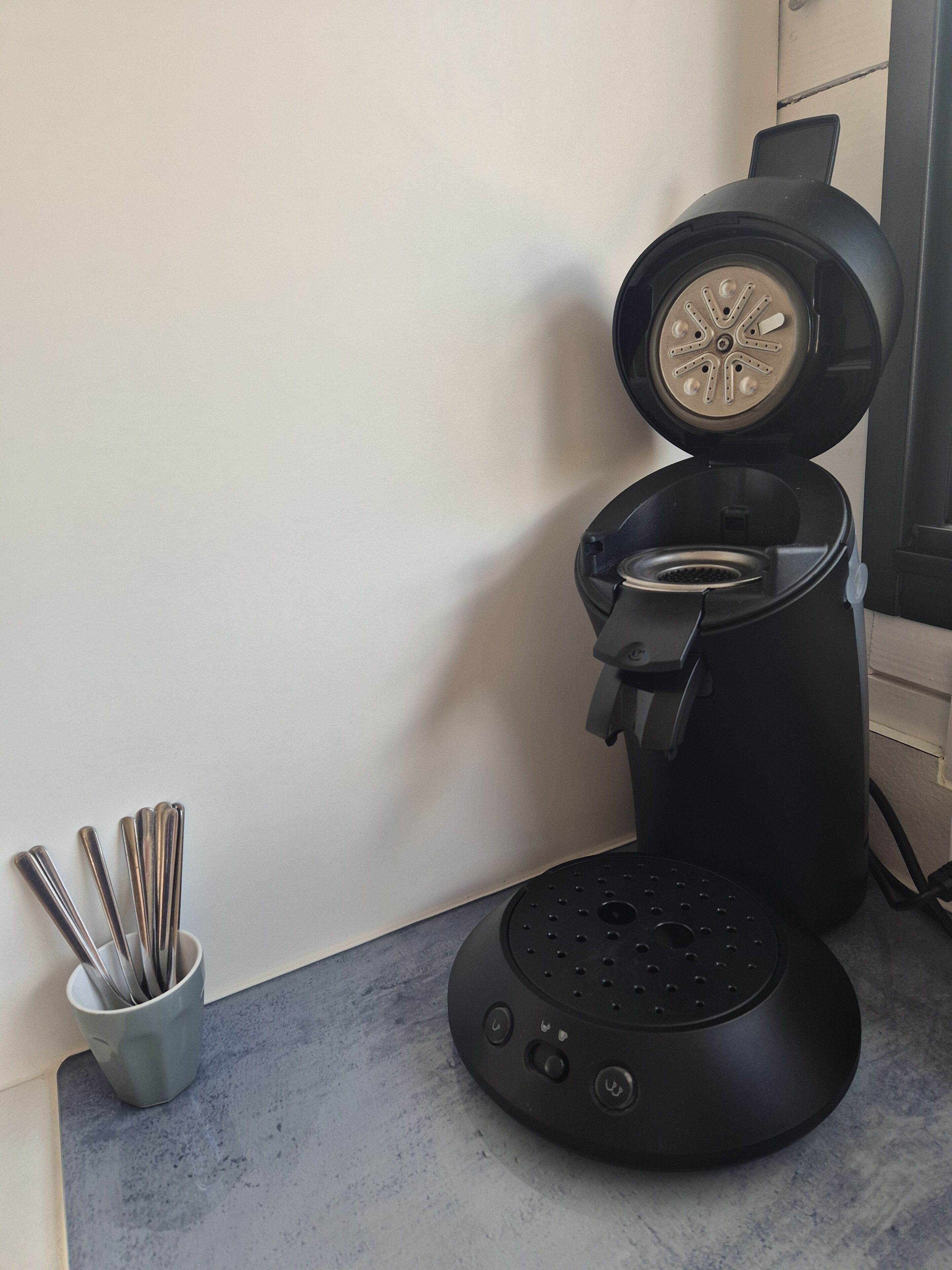 Une cuisine équipée d’une machine à café, d’un ensemble d’ustensiles et d’une fenêtre.