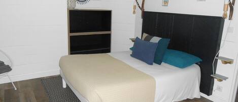 Un dormitorio con una cama, una mesita de noche, un espejo y una estantería.