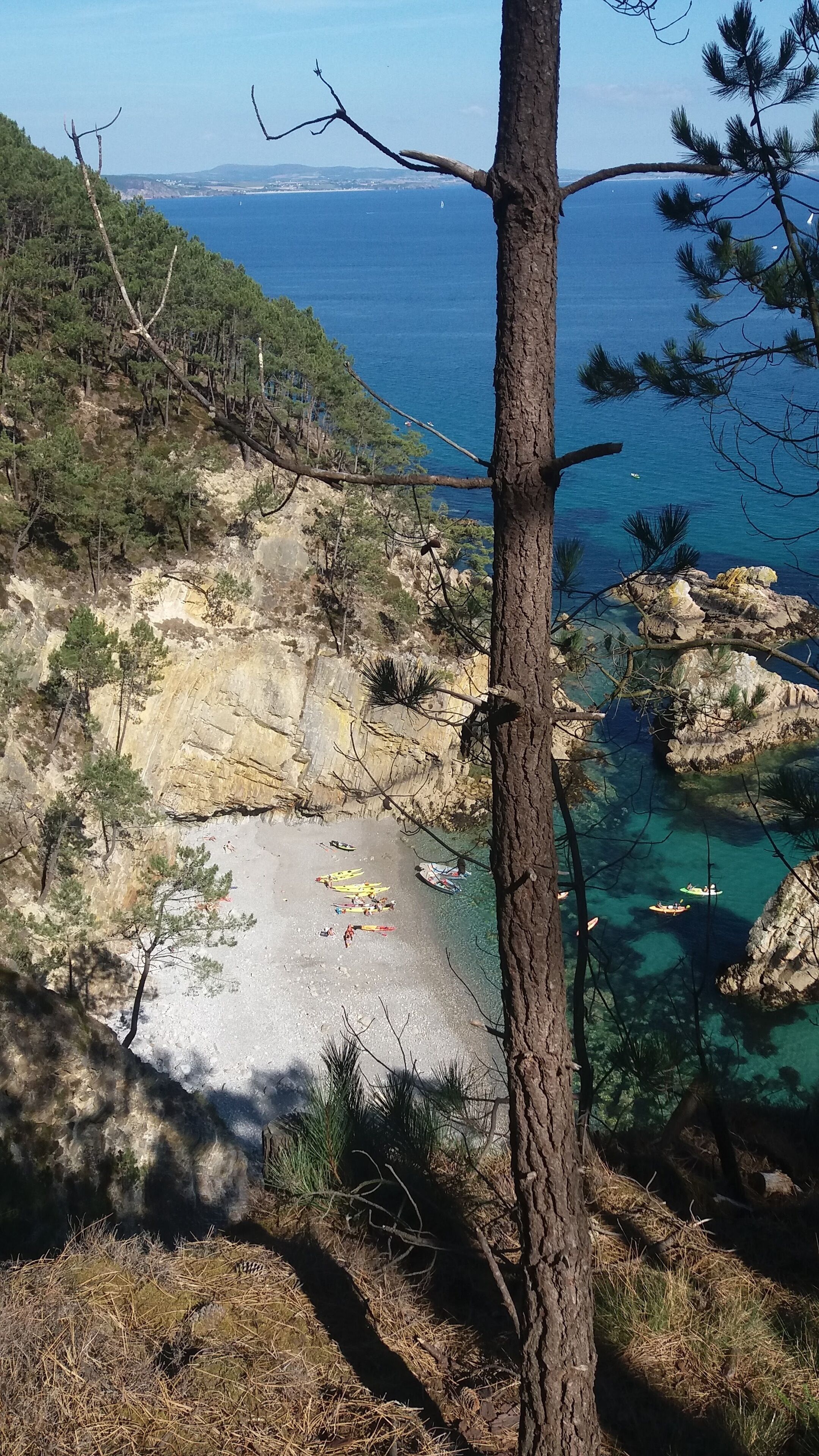 Eine Küstenlandschaft mit felsigem Gelände, klarem, blauem Meer und einem Sandstrand.