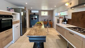 A modern kitchen with a central island, built-in appliances, and a dining area. - Adorable villa with private swimming pool and a superb view of the mountains (Eyragues)