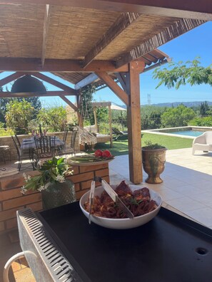 Un patio al aire libre con una parrilla, zona de estar y vistas del paisaje.