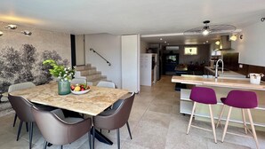 A modern kitchen with a central island, a dining area with a marble table, and a staircase leading to an upper level. - Adorable villa with private swimming pool and a superb view of the mountains (Eyragues)