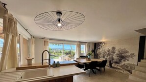 A modern kitchen with a central island, a dining area with a view, and a staircase leading to an upper level. - Adorable villa with private swimming pool and a superb view of the mountains (Eyragues)