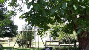 An outdoor seating area with wicker furniture and a swing set. - Old house located on an apple-red fruit farm (Savignac-Lédrier)