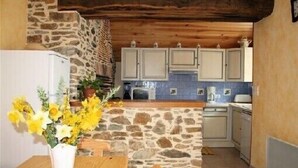 A rustic kitchen with stone walls, wooden ceiling beams, and white cabinets. - Old house located on an apple-red fruit farm (Savignac-Lédrier)