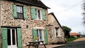 A stone building with green shutters, a picnic table, and a small garden area. - Old house located on an apple-red fruit farm (Savignac-Lédrier)