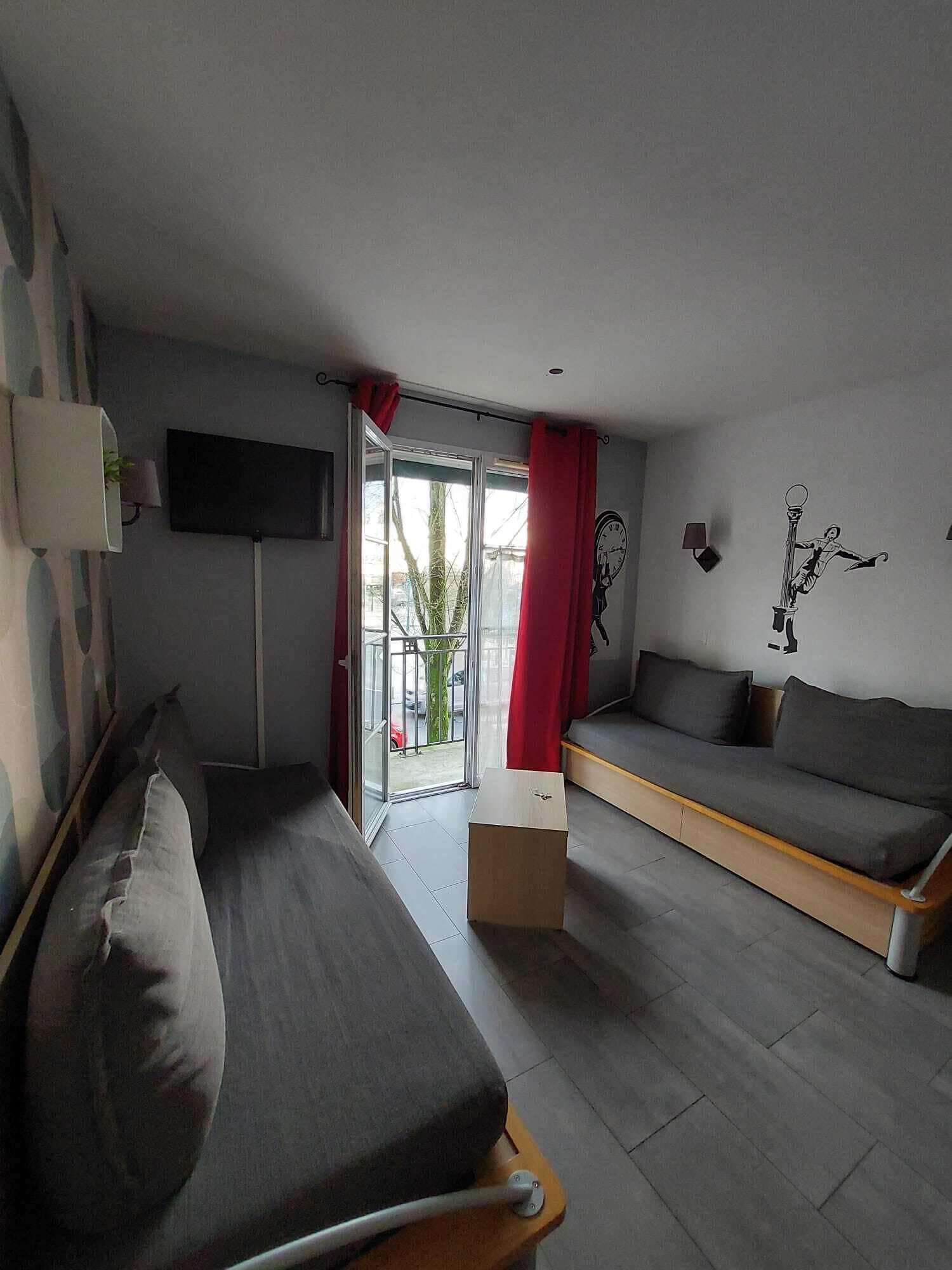 Une chambre d’hôtel moderne équipée d’un lit, d’un canapé, d’une télévision et d’une fenêtre avec des rideaux.