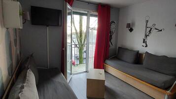 Une chambre d’hôtel moderne équipée d’un lit, d’un canapé, d’une télévision et d’une fenêtre avec des rideaux.