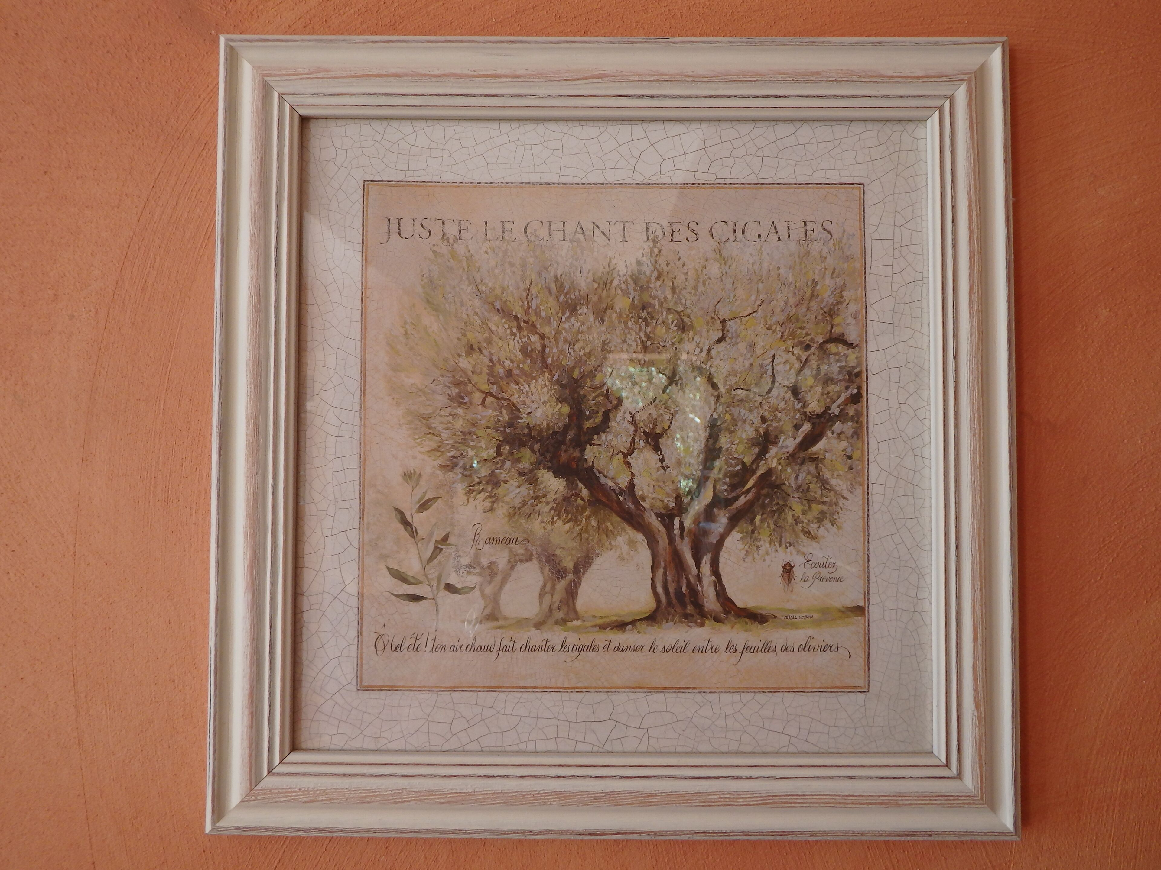 A framed artwork of a tree with the text "JUSTE LE CHANT DES CIGALES" and "Écoute le chant des cigales" on a textured wall.