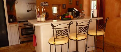 Une cuisine dotée d’un îlot central, de tabourets de bar, d’une cuisinière et d’un évier.