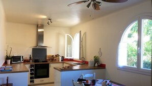 A compact kitchen with a microwave, stove, and sink. There is a dining area with a table and chairs. - Completely renovated house with swimming pool, garden, parking, A/C, in Argelès (Argelès-Sur-Mer)
