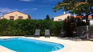 A swimming pool with two lounge chairs, surrounded by a fence and lush greenery. - Completely renovated house with swimming pool, garden, parking, A/C, in Argelès (Argelès-Sur-Mer)