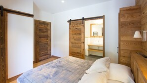 Une chambre à coucher comprenant un lit, une armoire en bois et une porte coulissante donnant accès à une salle de bain.