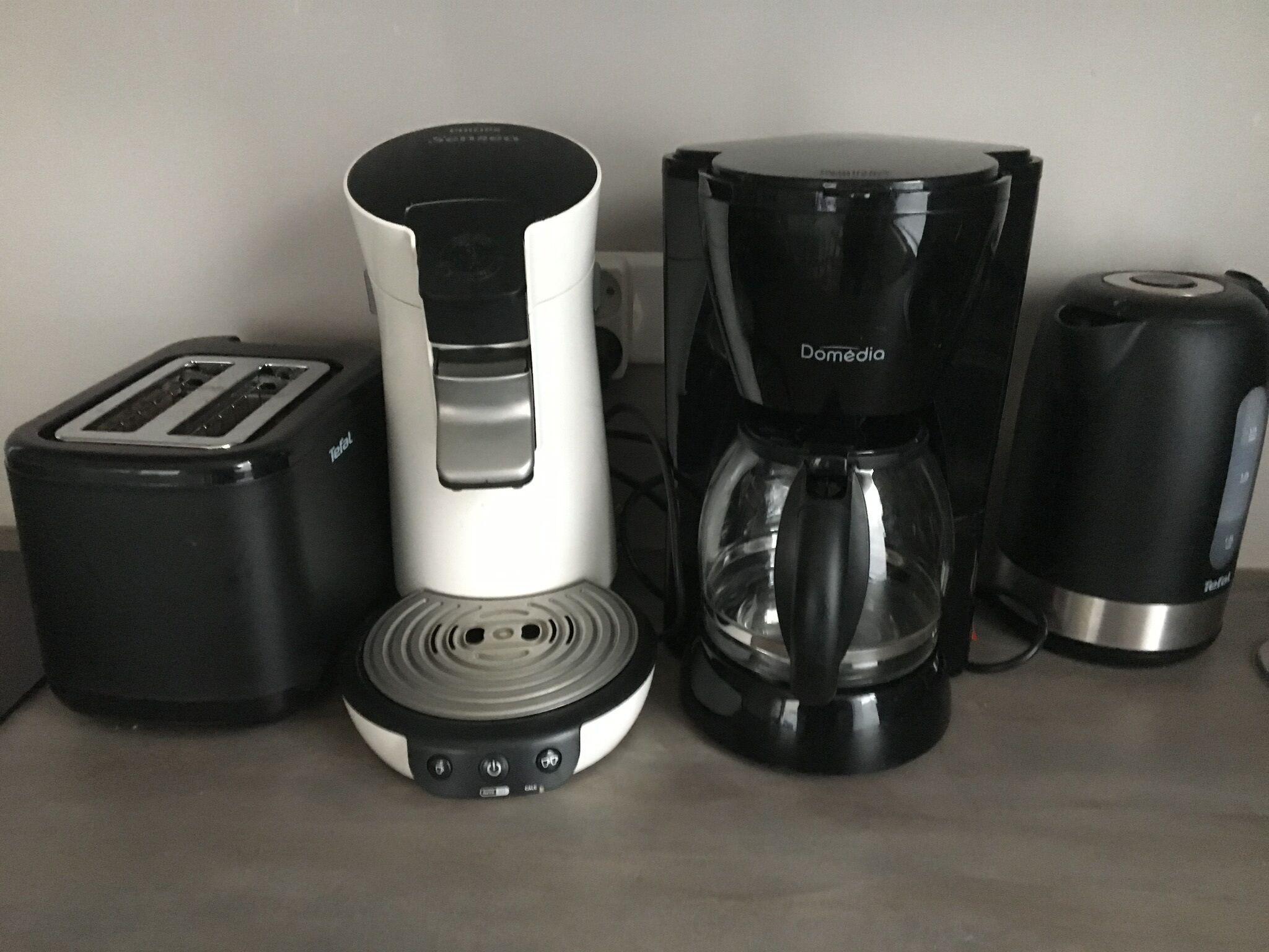 Een keuken met een broodrooster, koffiezetapparaat en blender.