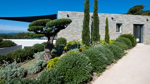 A modern building with a stone facade, surrounded by well-maintained gardens and tall trees. - Magnificent villa with breathtaking views of Palombaggia beach Private sea access (Porto-Vecchio)