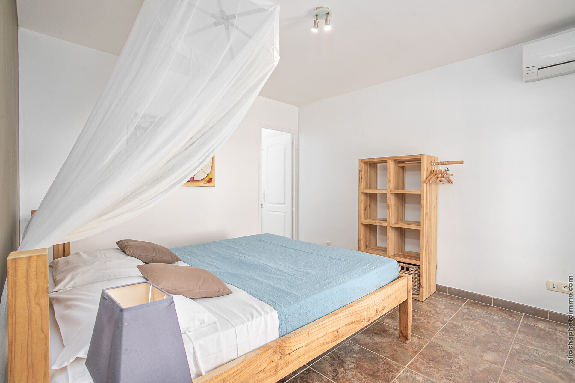 Une chambre à coucher avec un lit, une armoire en bois et un ventilateur de plafond.