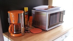 A kitchen with a microwave, coffee maker, and a bottle of insect repellent on the counter. - Pavillon Hourtin-ville, near the lake (Hourtin)