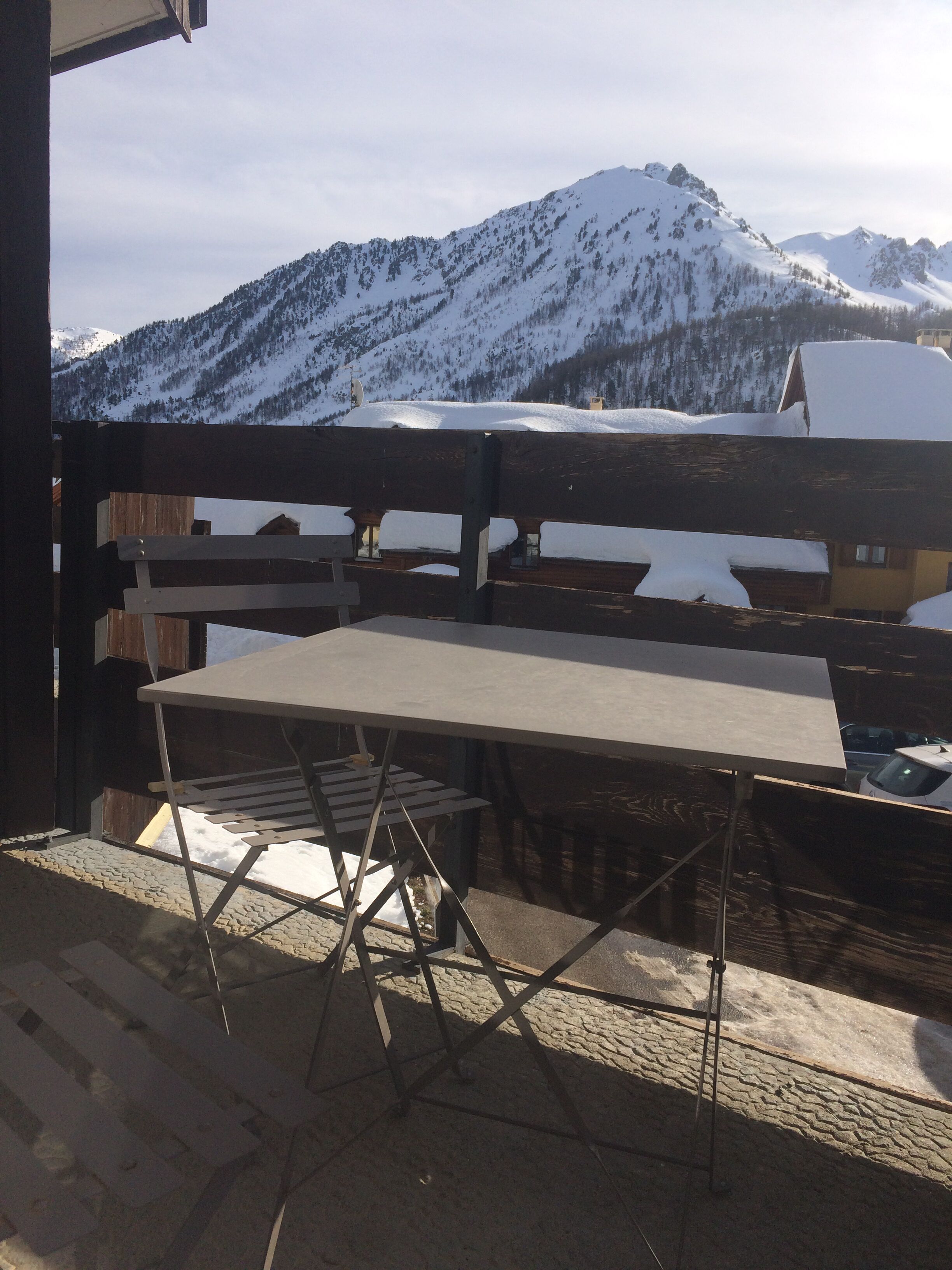 A wooden table and chairs set up on a balcony with a mountain view.