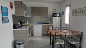 Eine kompakte Küche mit Geschirrspüler, Mikrowelle und einem Essbereich mit Tisch und Stühlen.